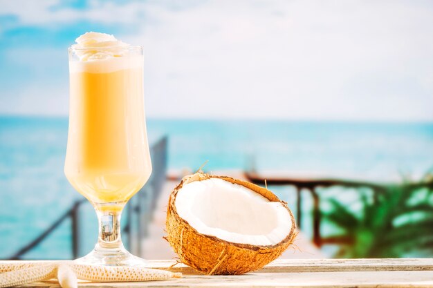 Glass of soft yellow drink starfish and cracked coconut