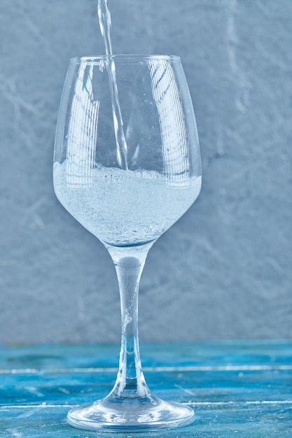 Free photo a glass of sparkling water on blue surface