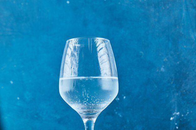 A glass of sparkling water on blue surface