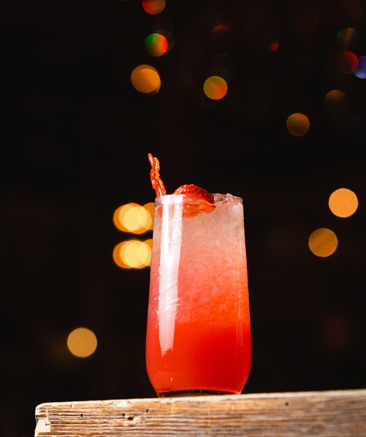 A glass of strawberry cocktail garnished with strawberry