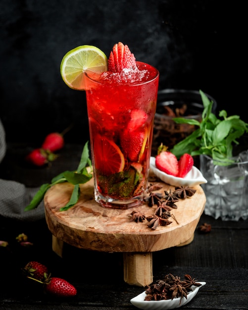 A glass of strawberry cocktail with strawberries and lime slices