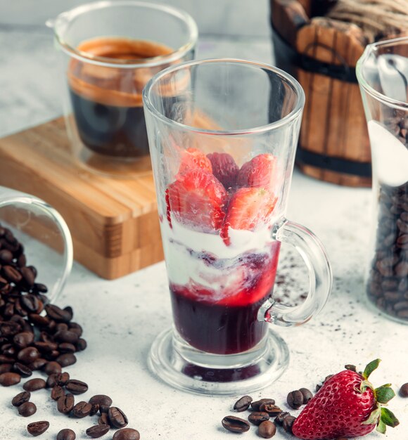 Glass of strawberry sauce topped with ice cream and strawberries