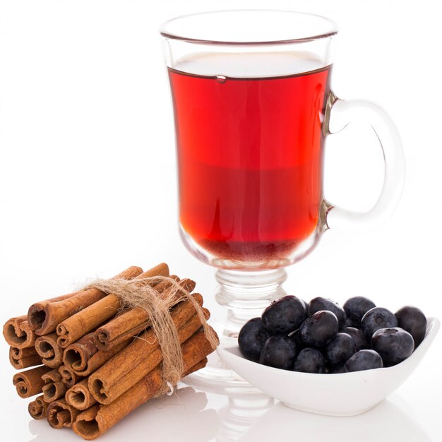 Glass of tea a stack of cinnamon and a plate with blueberries