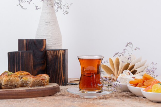 Glass of tea, sweets and traditional various baklavas on marble table.