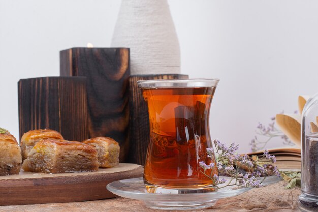 Glass of tea and traditional various baklavas on marble table.