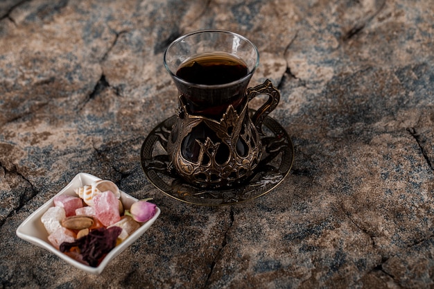 Free photo a glass of tea with nuts and sweets in a white saucer