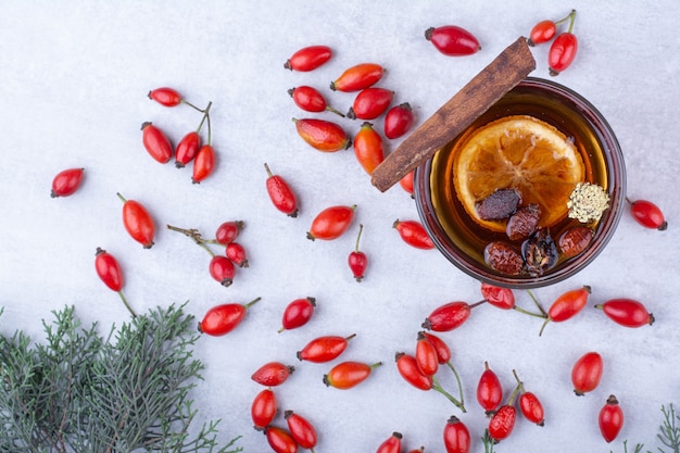 Foto gratuita bicchiere di tè con cinorrodi, stecca di cannella e fetta d'arancia.