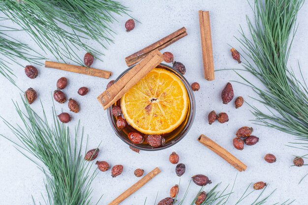 Glass of tea with rosehips and cinnamons on marble surface. 