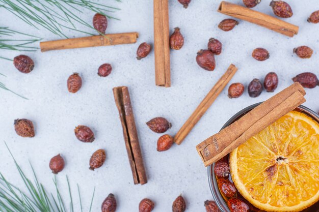 Glass of tea with rosehips and cinnamons on marble surface. 