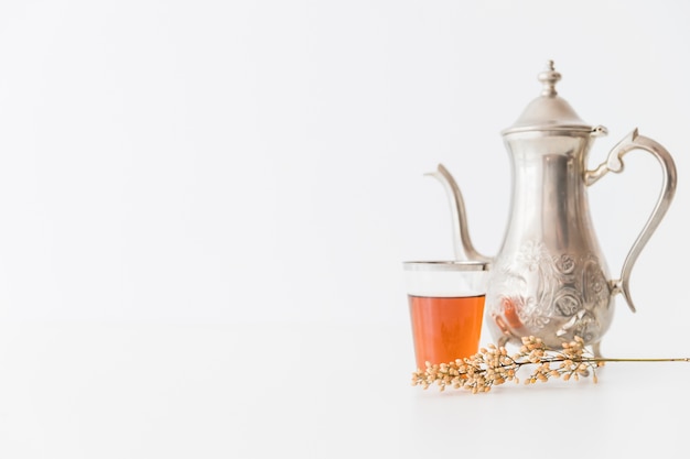 Bicchiere di tè con teiera e ramo
