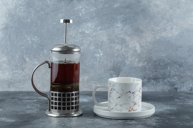 Free photo glass teapot with cup on grey table.