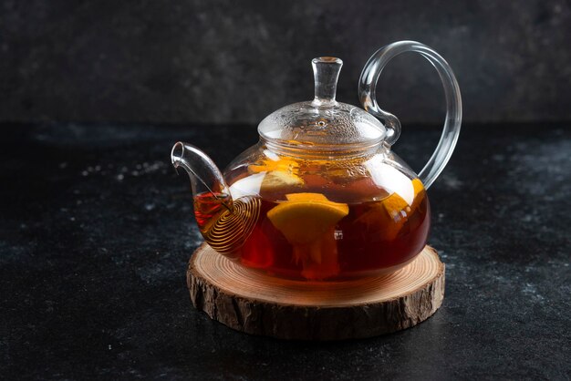 A glass teapot with hot tea and slices of lemon.