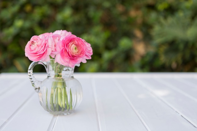 Glass vase with flowers in pink tones