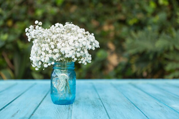 青色の木製テーブルの上に白い花とガラスの花瓶