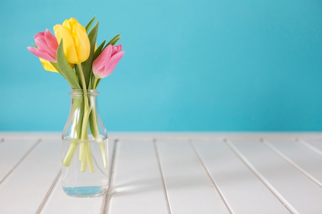 Free photo glass vase with yellow and pink tulips