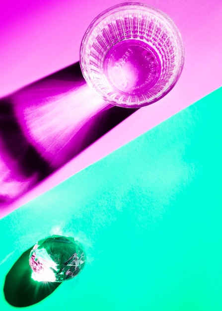 Glass of water and crystal with bright shadow on dual background