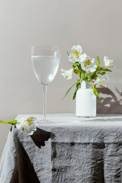 Glass of water and flowers on table