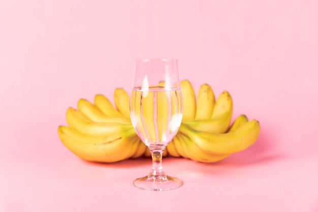 Glass of water with bananas in background