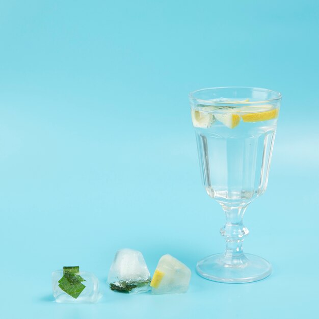 Glass of water with lemon on blue background
