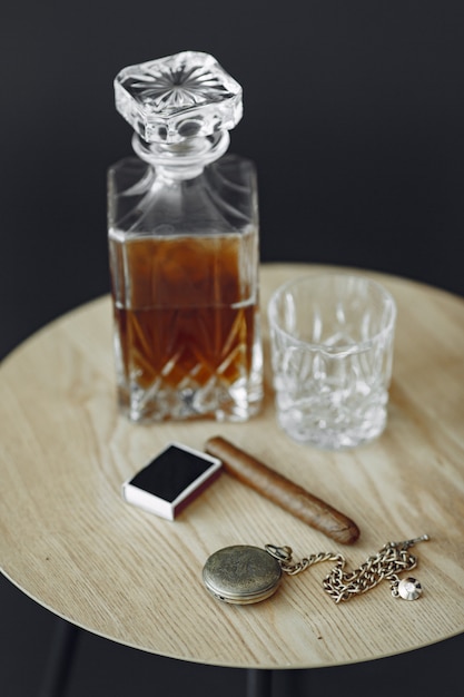 Glass of whiskey with cigar on table. Close up photo of alcohol and cigar.