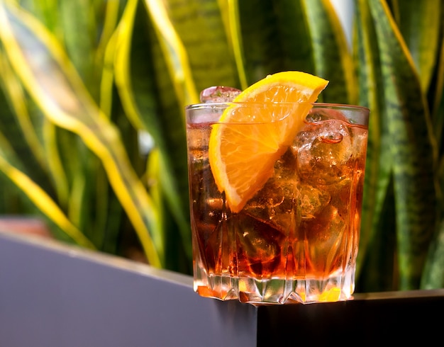 A glass of whisky with sliced lemon and ice side view