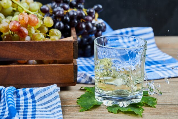 ブドウと木製のテーブルの上の白ワインのグラス。