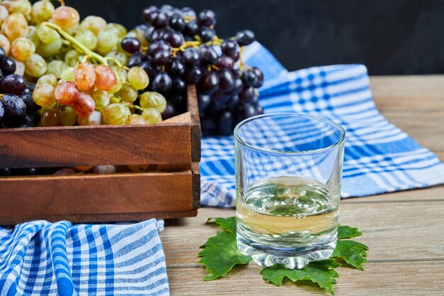A glass of white wone on wooden table with grapes.