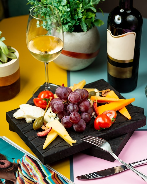 Glass of wine served with grape, cheese and tomato