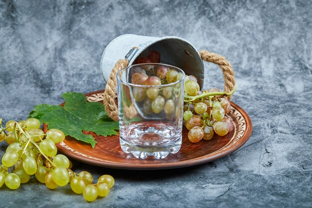A glass of wine with a bunch of green grapes. 