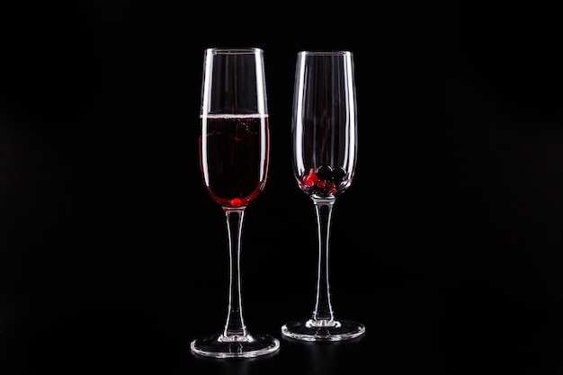 ベリーと赤いシャンパンアルコールカクテルのガラスは、黒の背景に立つ