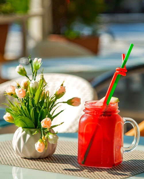 Foto gratuita bicchiere con succo di anguria fredda e un vaso di fiori