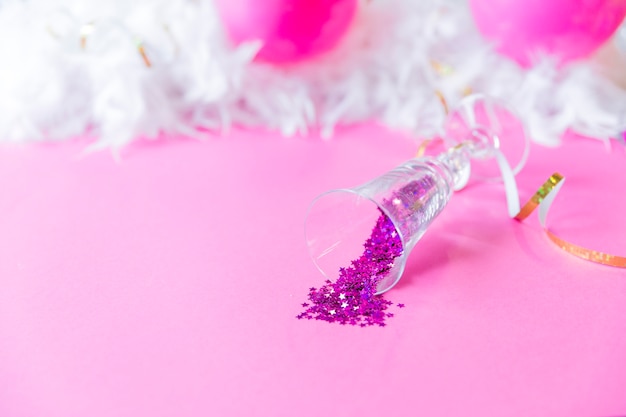 Glass with confetti near feathers