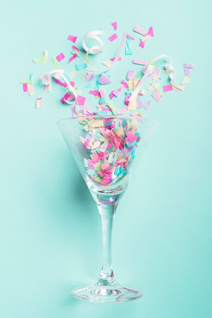 Glass with confetti on turquoise background