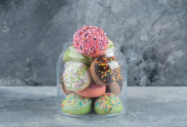 Glass with full of cookies on marble table.