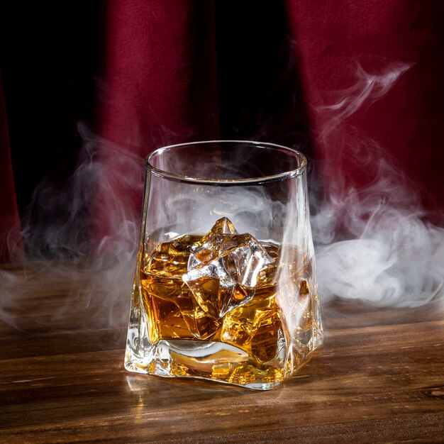 Glass with ice cube and smoke