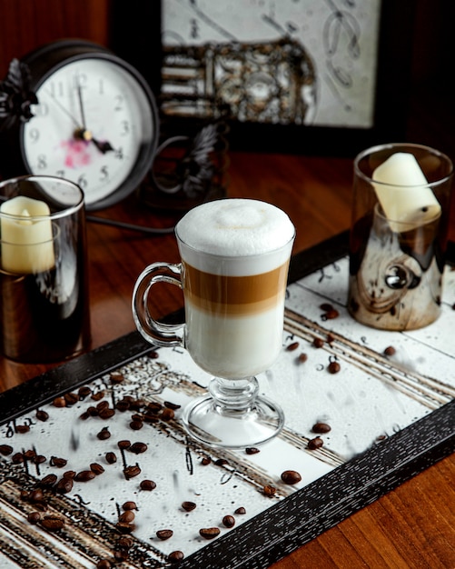 Foto gratuita vetro con latte e chicchi di caffè sul tavolo