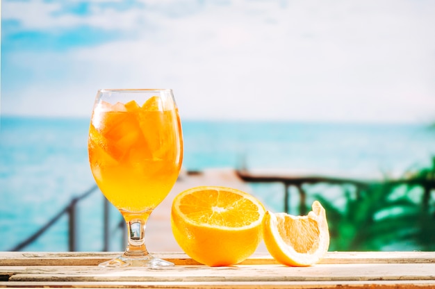 ガラスのオレンジ色の飲み物とスライスされたオレンジ色の木製のテーブル