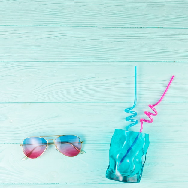 Glass with straws near sunglasses