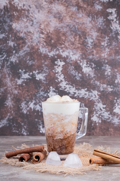 Glass with tasty drink and cinnamon on marble surface .