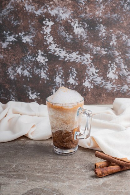 Glass with tasty drink and cinnamon on marble surface .