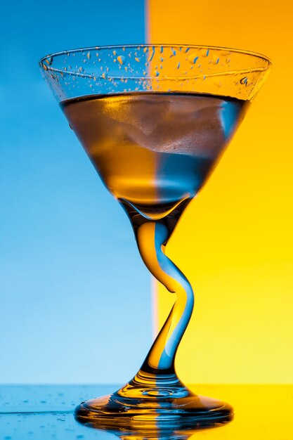 Glass with water over blue and yellow wall