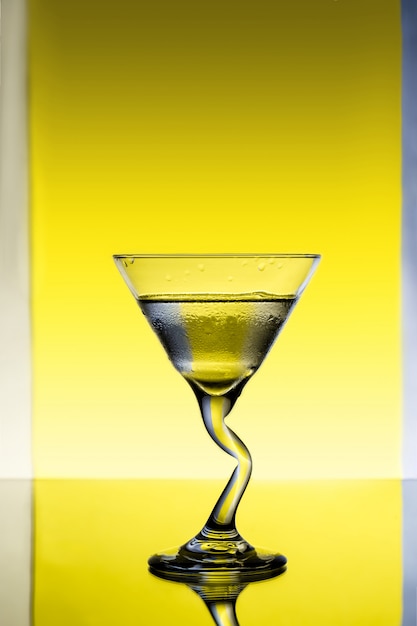 Glass with water over grey and yellow background.