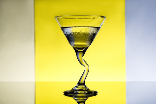 Glass with water over grey and yellow surface