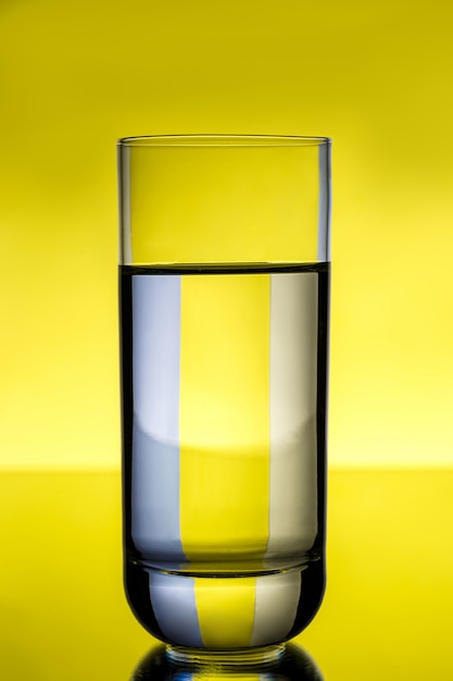 Glass with water over yellow wall