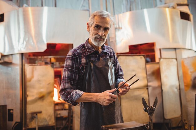 Glassblower holding tongs at glassblowing factory