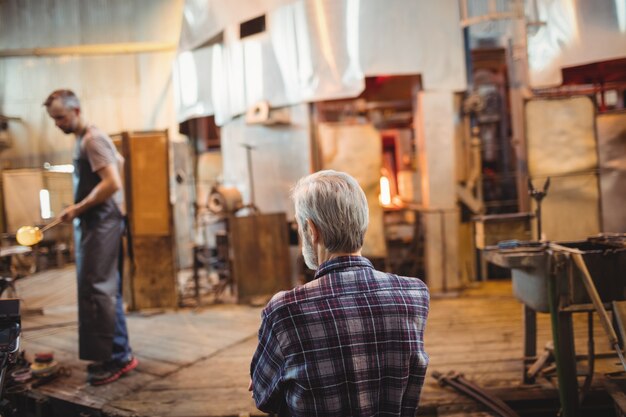 Glassblower looking at coworker working