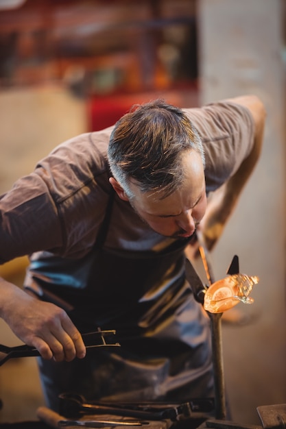Free photo glassblower shaping a molten glass