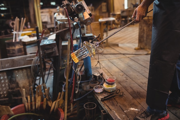 Free photo glassblower shaping a molten glass