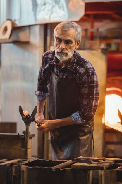 Glassblower shaping a molten glass