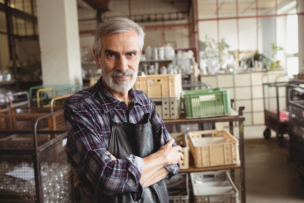 Glassblower standing with arms crossed at glassblowing factory